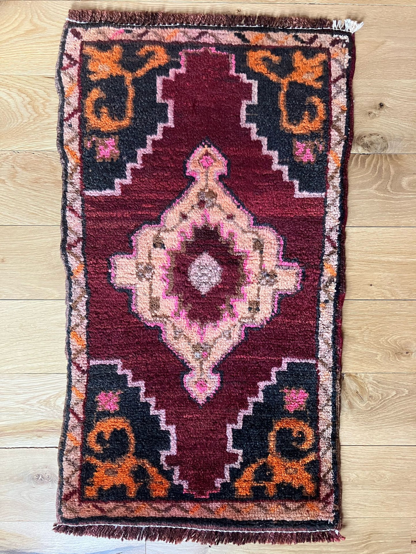Handmade vintage Turkish entryway rug made of a cotton foundation and a wool pile, featuring red, black, and orange colors.