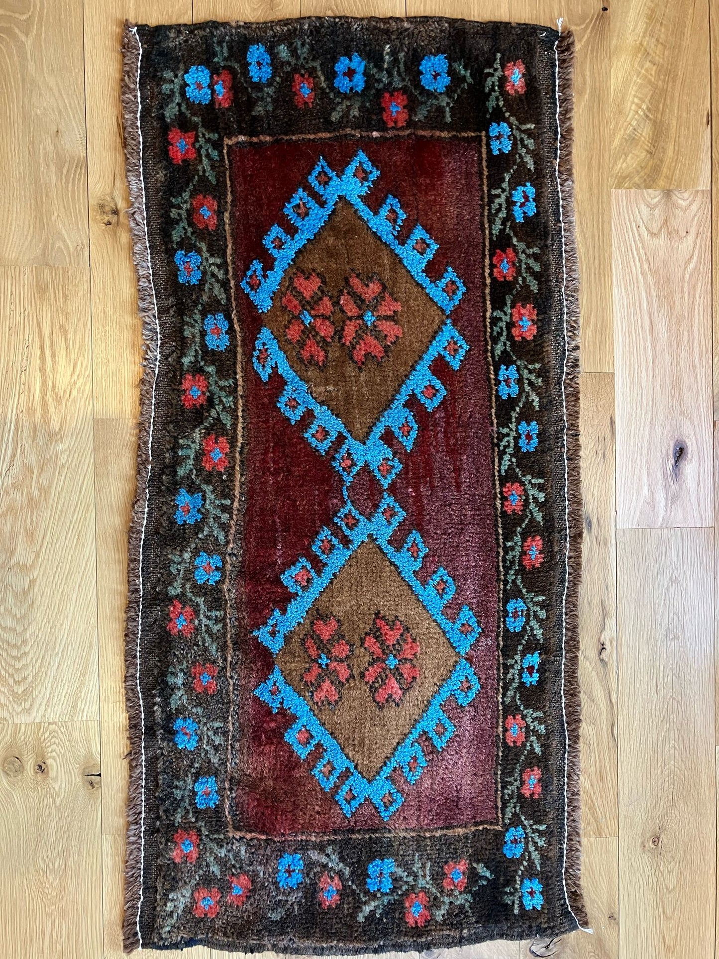 Handmade vintage Turkish entryway rug made of 100% wool, featuring red, blue, and brown colors.