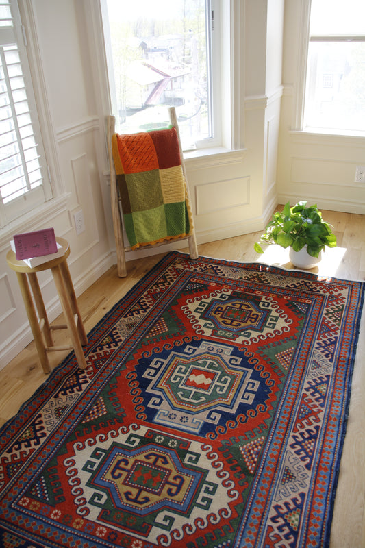Handmade vintage Azerbaijani medium rug made of a cotton foundation and a wool pile, featuring  red, blue, and green colors.