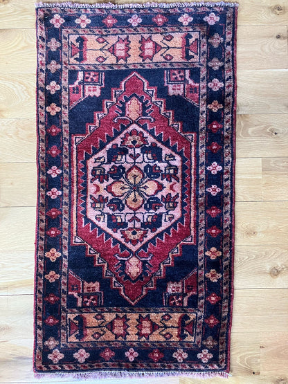 Handmade vintage Turkish entryway rug made of 100% wool, featuring red and black colors.   