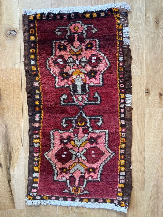 Handmade vintage Turkish entryway rug made of a cotton foundation and a wool pile, featuring  a red background.
