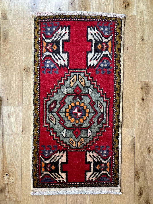 Handmade vintage Turkish entryway rug made of a cotton foundation and a wool pile, featuring red, white and black colors.