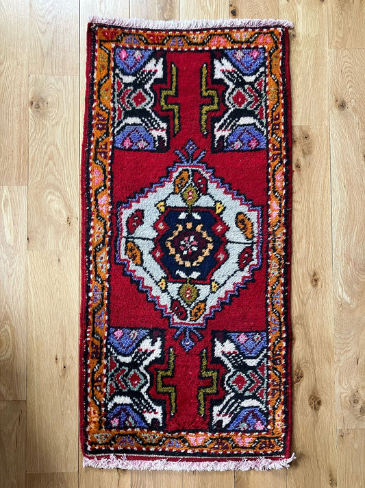 Handmade vintage Turkish entryway rug made of a cotton foundation and a wool pile, featuring red, white and black colors.