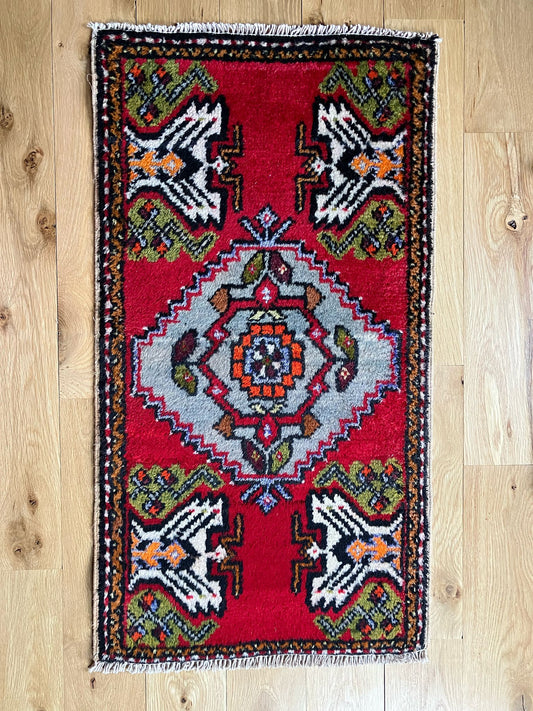 Handmade vintage Turkish entryway rug made of a cotton foundation and a wool pile, featuring red, white and black colors.