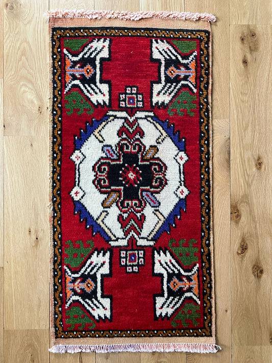 Handmade vintage Turkish entryway rug made of a cotton foundation and a wool pile, featuring red, green, white and black colors.